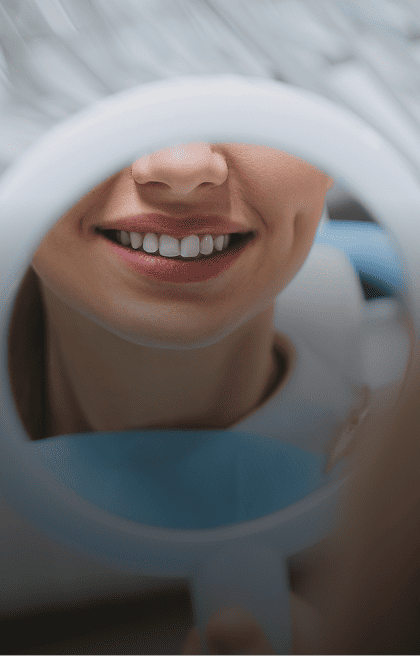 Mulher sorrindo em frente a um espelho no consultório odontológico