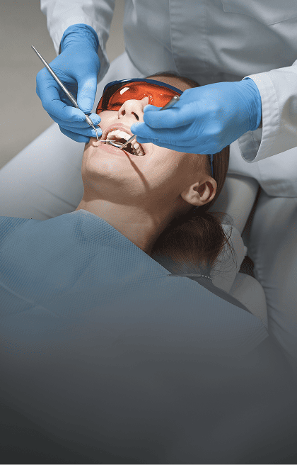 Mulher, com a boca aberta, recebendo tratamento odontológico pelo dentista